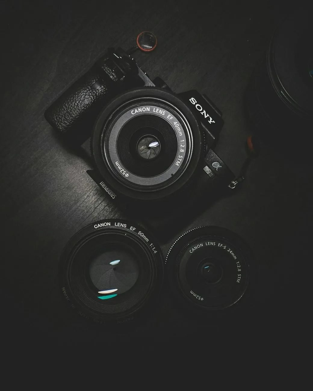 A camera body and two prime lenses arranged on a black surface.