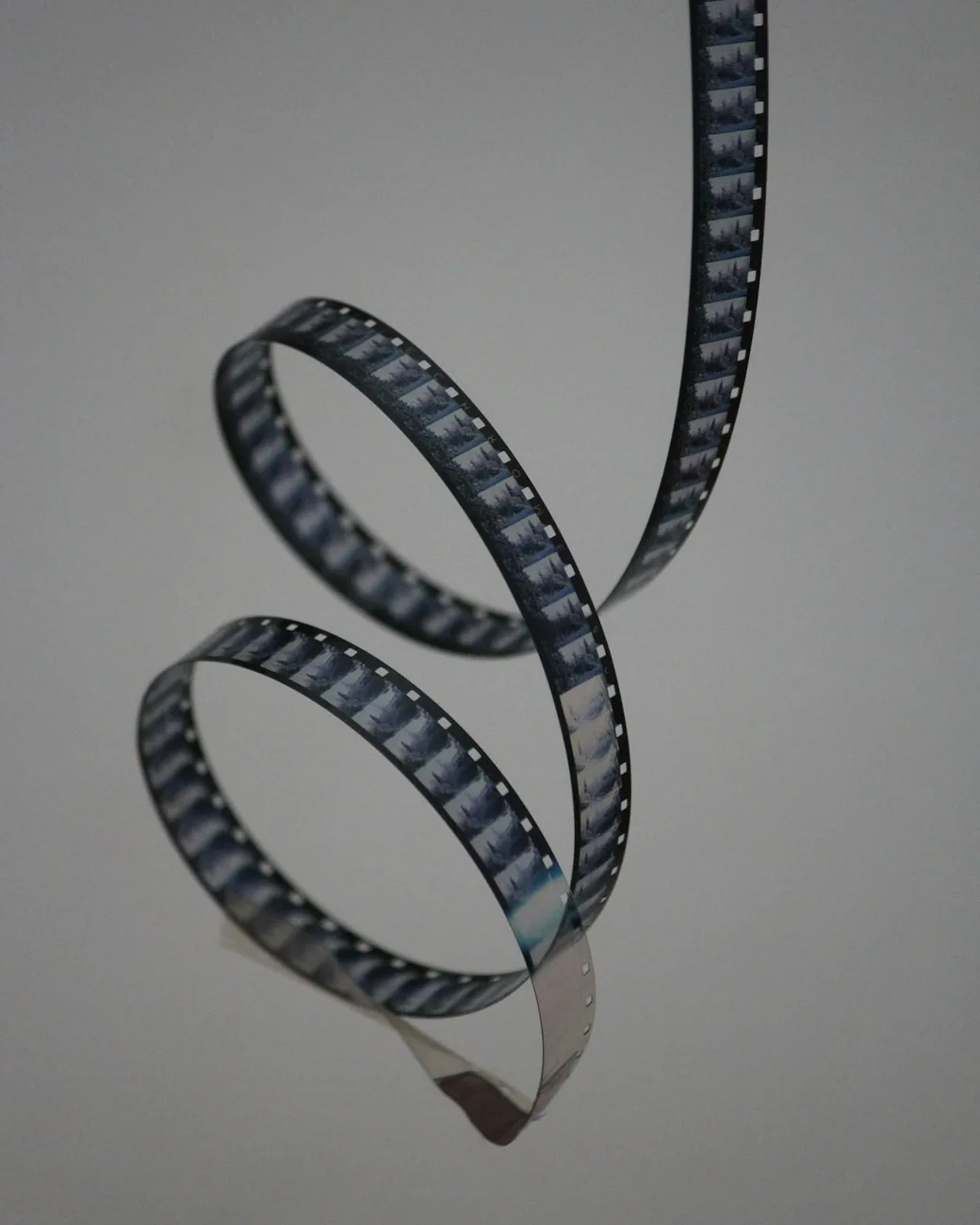 Two curled strips of 35mm film against a pale background.