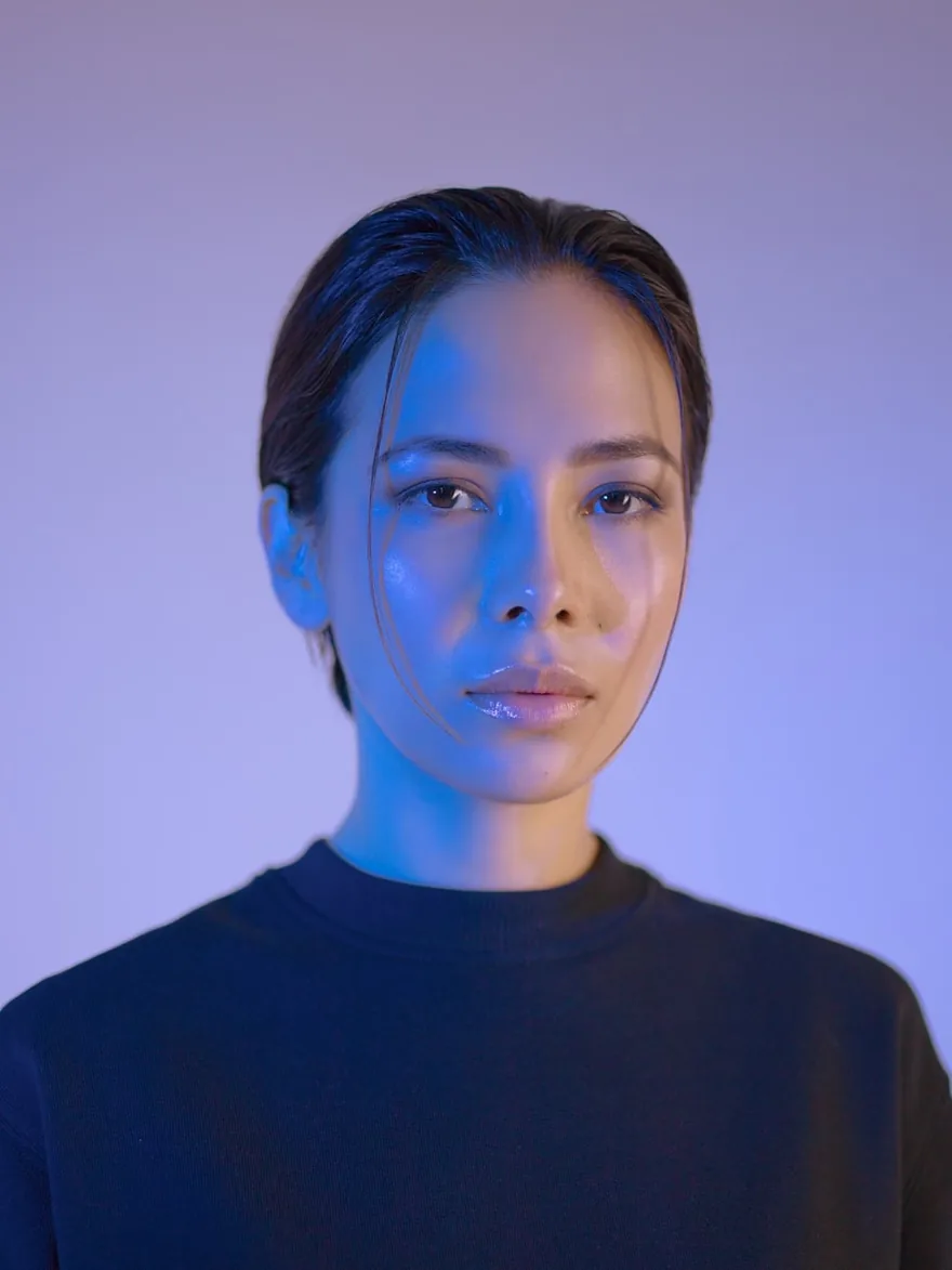Studio portrait against a dark backdrop, lit from one side.
